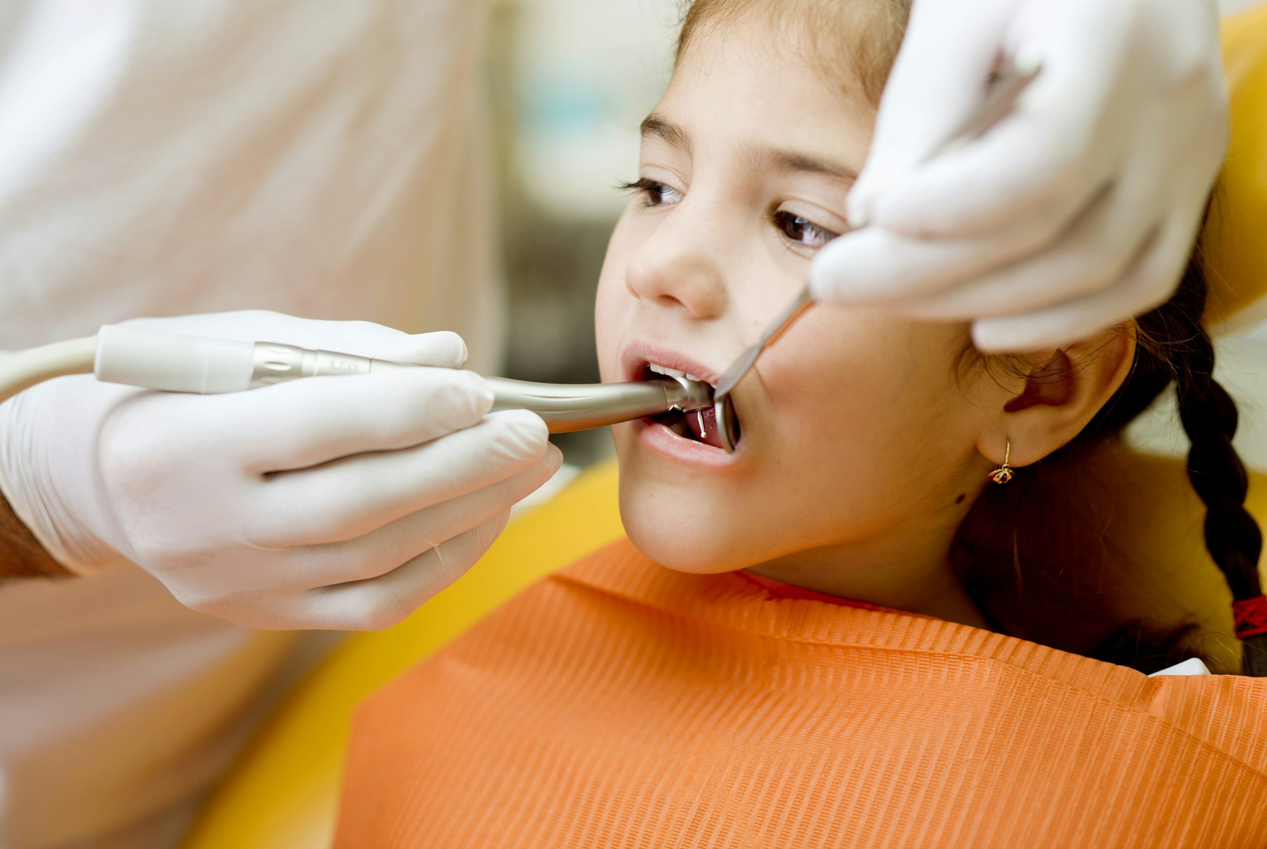 Dentist examining a child’s teeth during a dental procedure